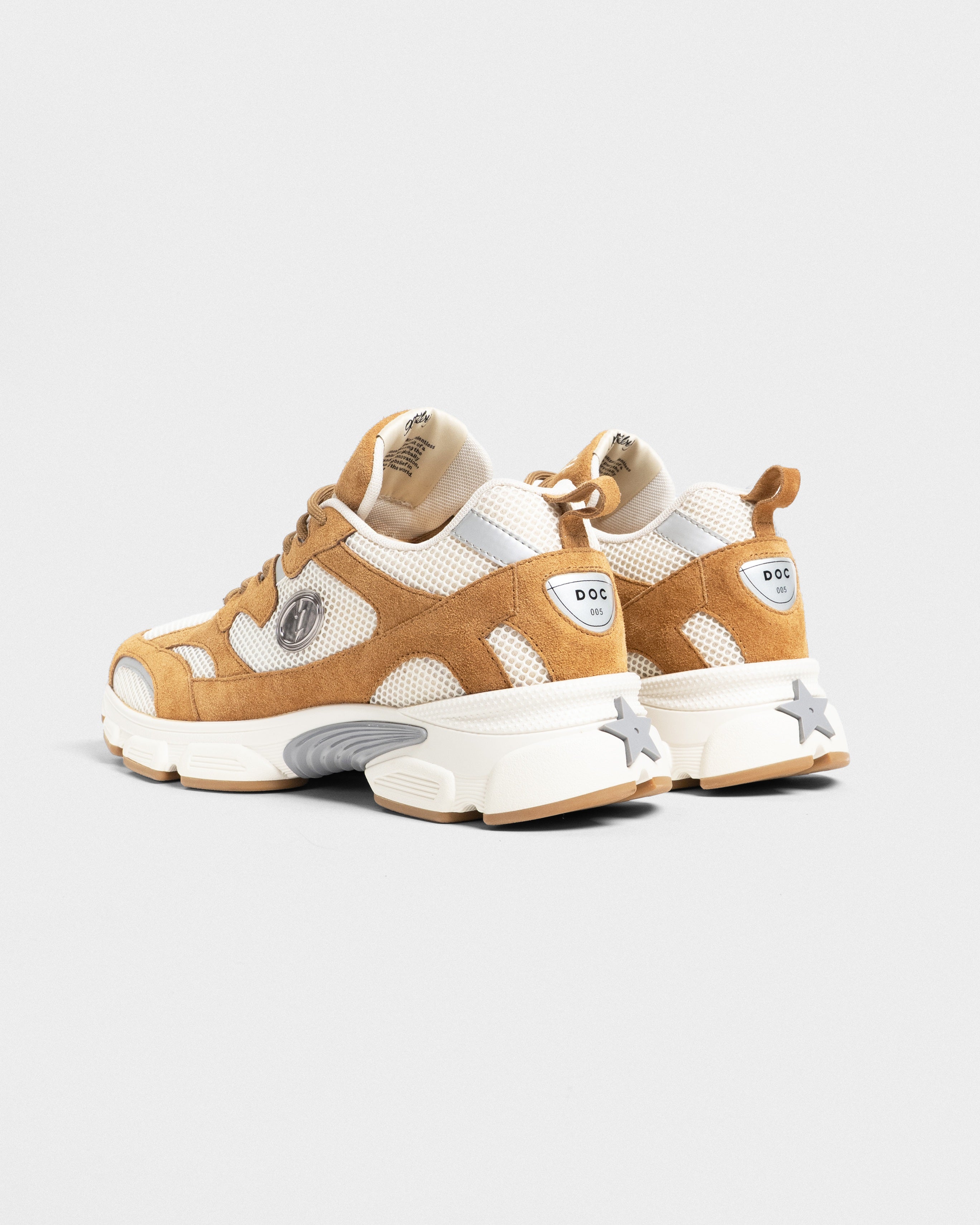 A pair of chunky low-top sneakers in tan suede and cream mesh, featuring a thick white sole with a star detail on the heel and a small circular 'DOC' logo on the heel counter.